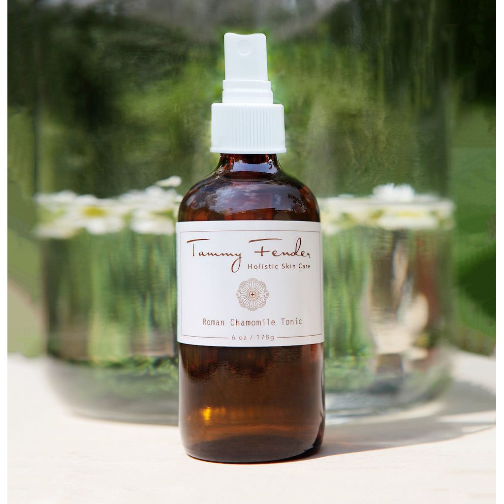 Amber glass bottle of tammy fender roman chamomile tonic skincare product with a reflective background.