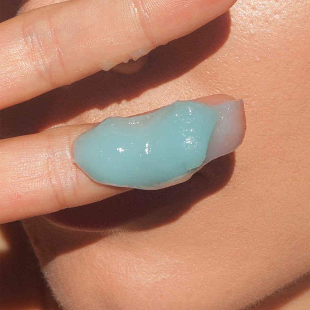 A close-up of a person's cheek with a dollop of blue gel-like substance on it.