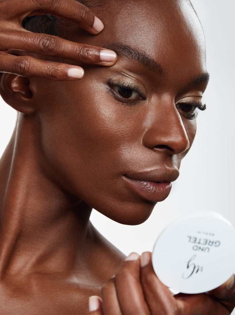 Model showing GOLDEN SAND 01: Sun-golden powder highlighter that brings a delicately iridescent metallic finish in a warm sand tone to the cheeks, nose, lips and eyes.