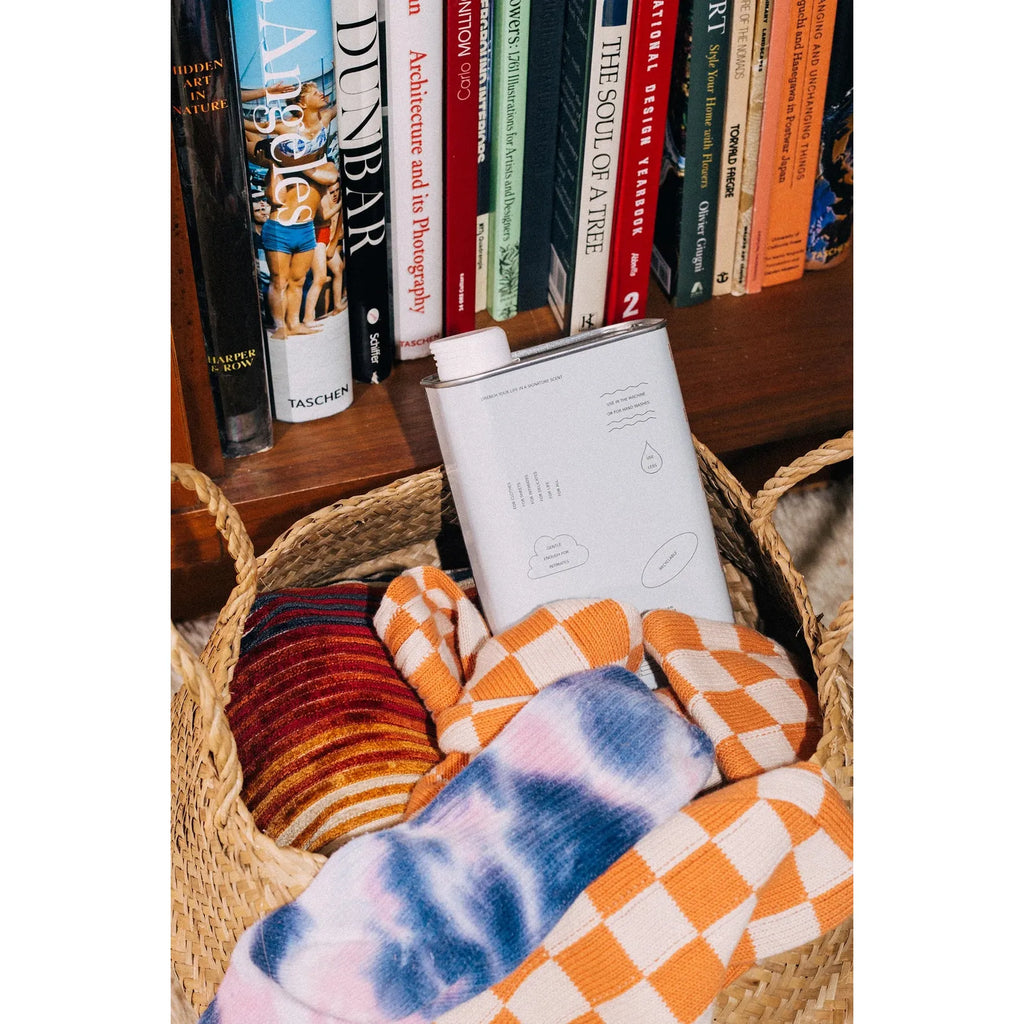 A basket filled with colorful socks and an open book in front of a bookshelf.