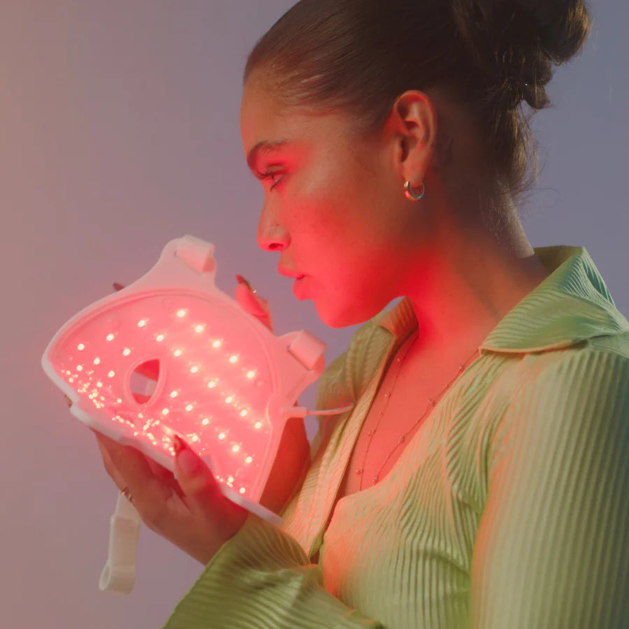 Woman holding a luminous, heart-shaped object, gazing intently at the glowing lights.