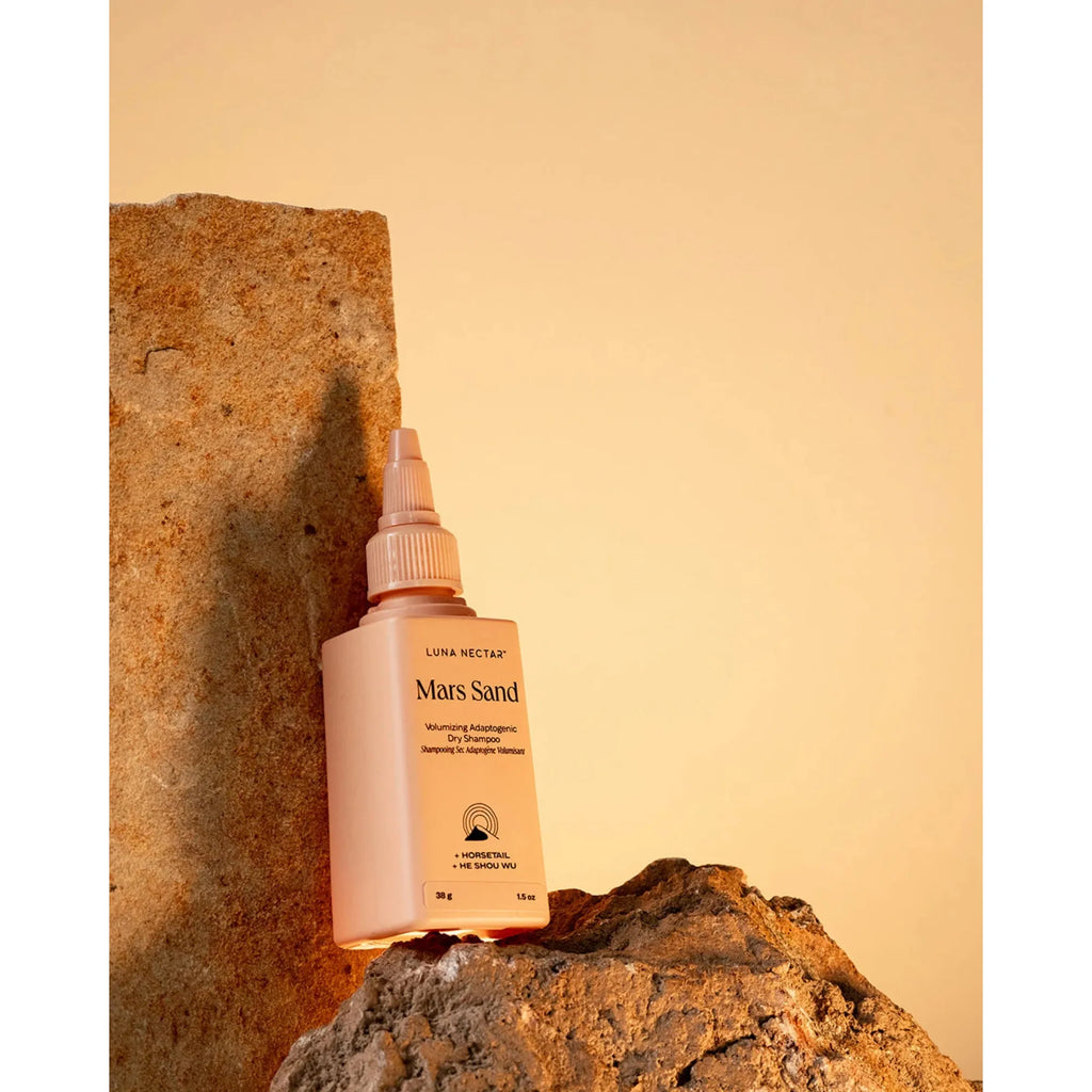 A skincare product bottle labeled "mars sand" positioned against a stone on a beige background.