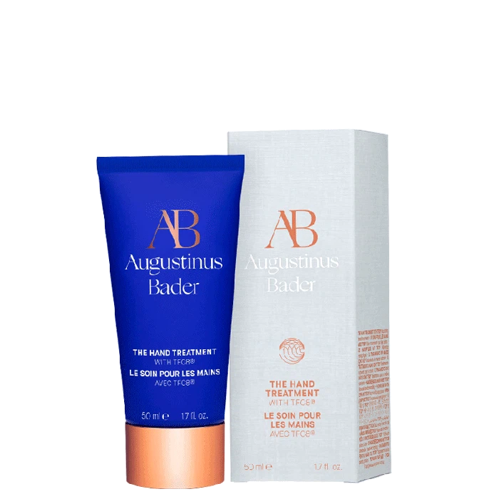 Blue and white tube of augustinus bader hand treatment cream next to its packaging box.