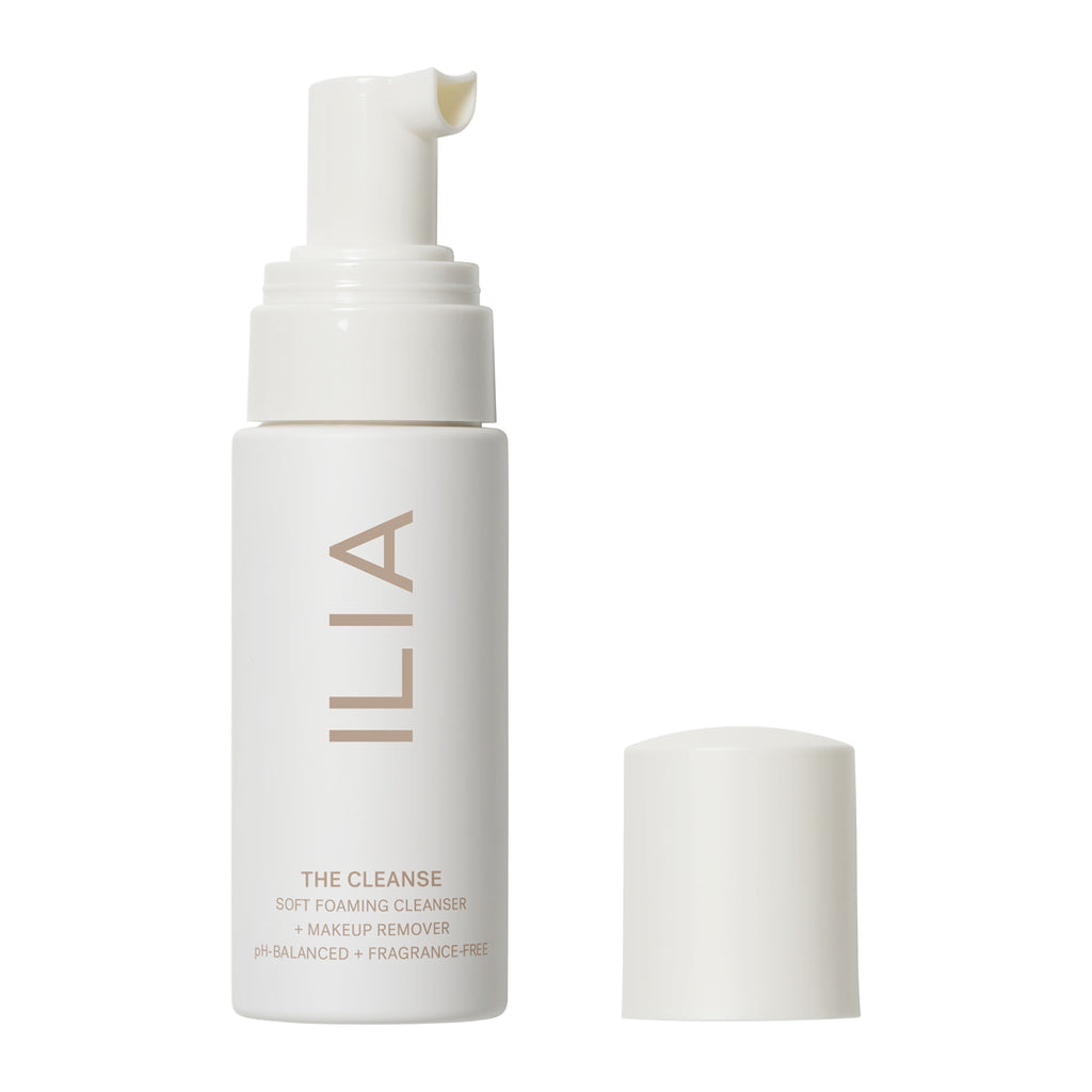 A bottle of ilia soft cleanse makeup remover with a pump dispenser and its cap placed beside it.