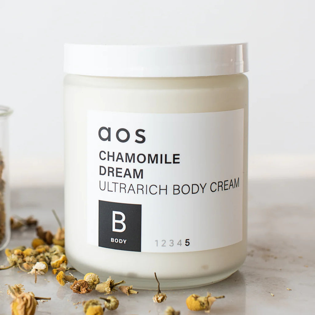 Jar of chamomile dream ultra-rich body cream with dried chamomile flowers scattered around it.
