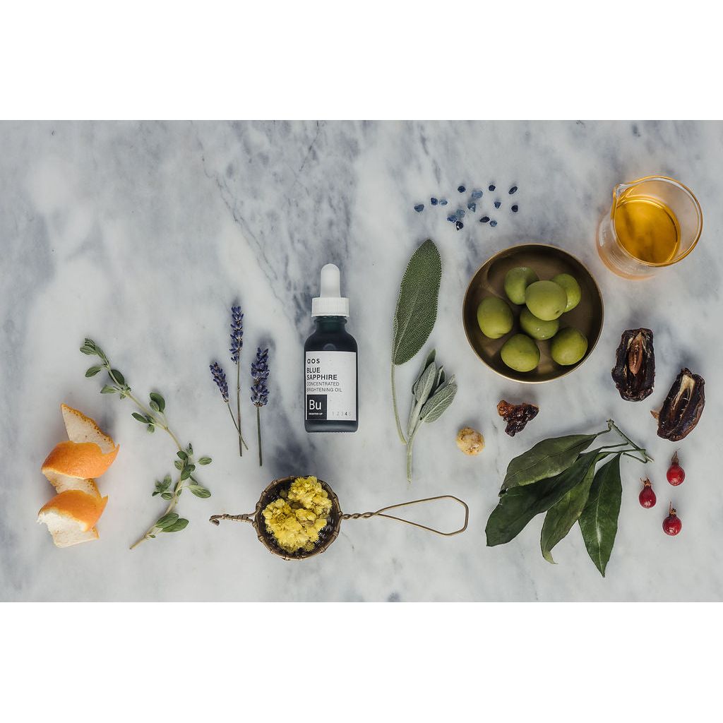 Flat lay of natural skincare products and botanical ingredients on a marble surface.