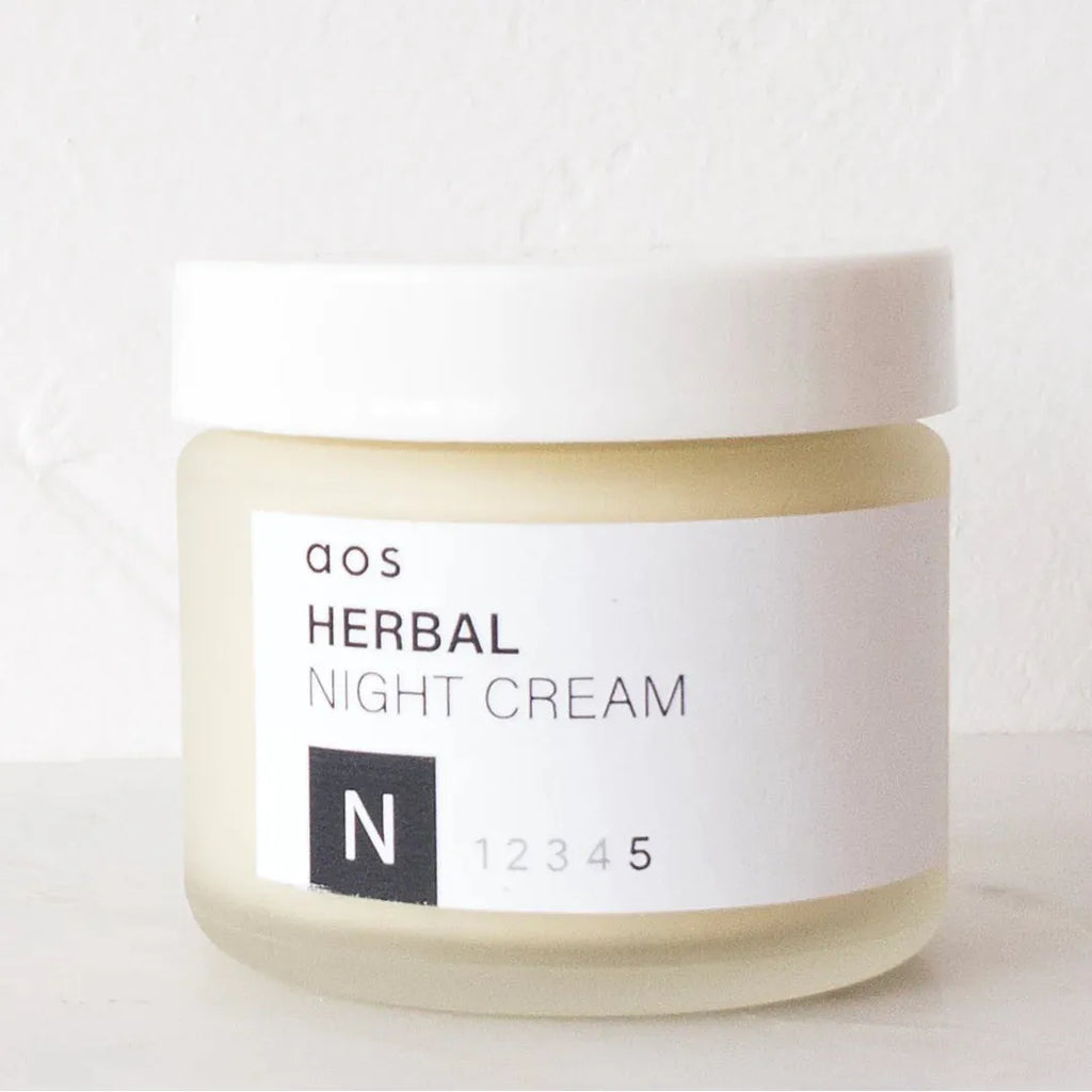 Jar of herbal night cream on a white surface.