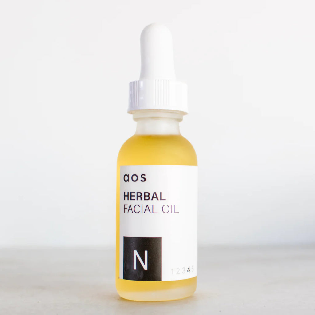 Glass dropper bottle labeled "herbal facial oil" on a neutral background.