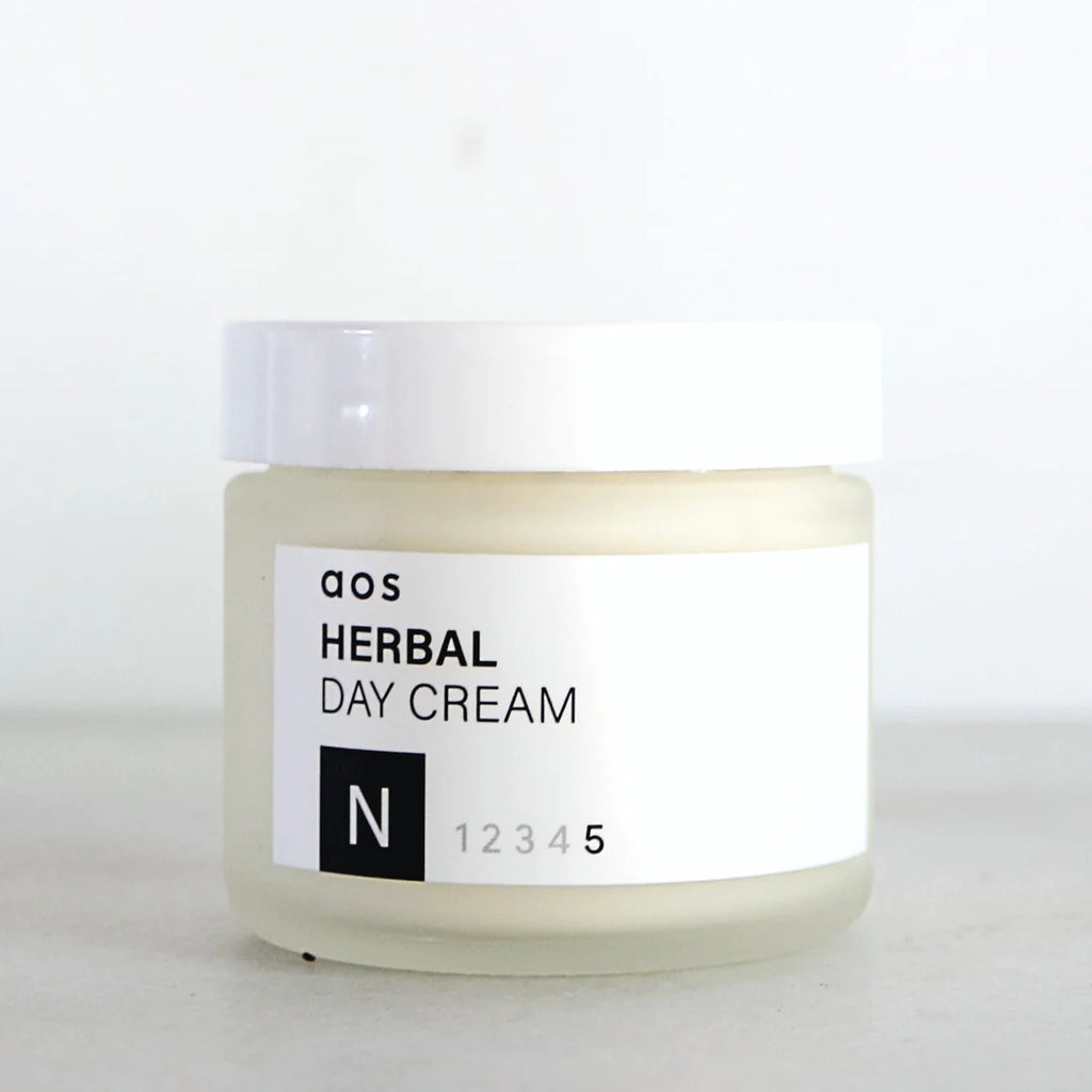 A jar of herbal day cream on a plain background.