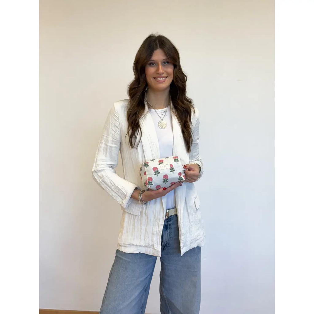 Model showing Medium toiletry bag with a zipper at the top and a side handle. Made with thin half-panama fabric with a floral pattern in pink and off-white tones