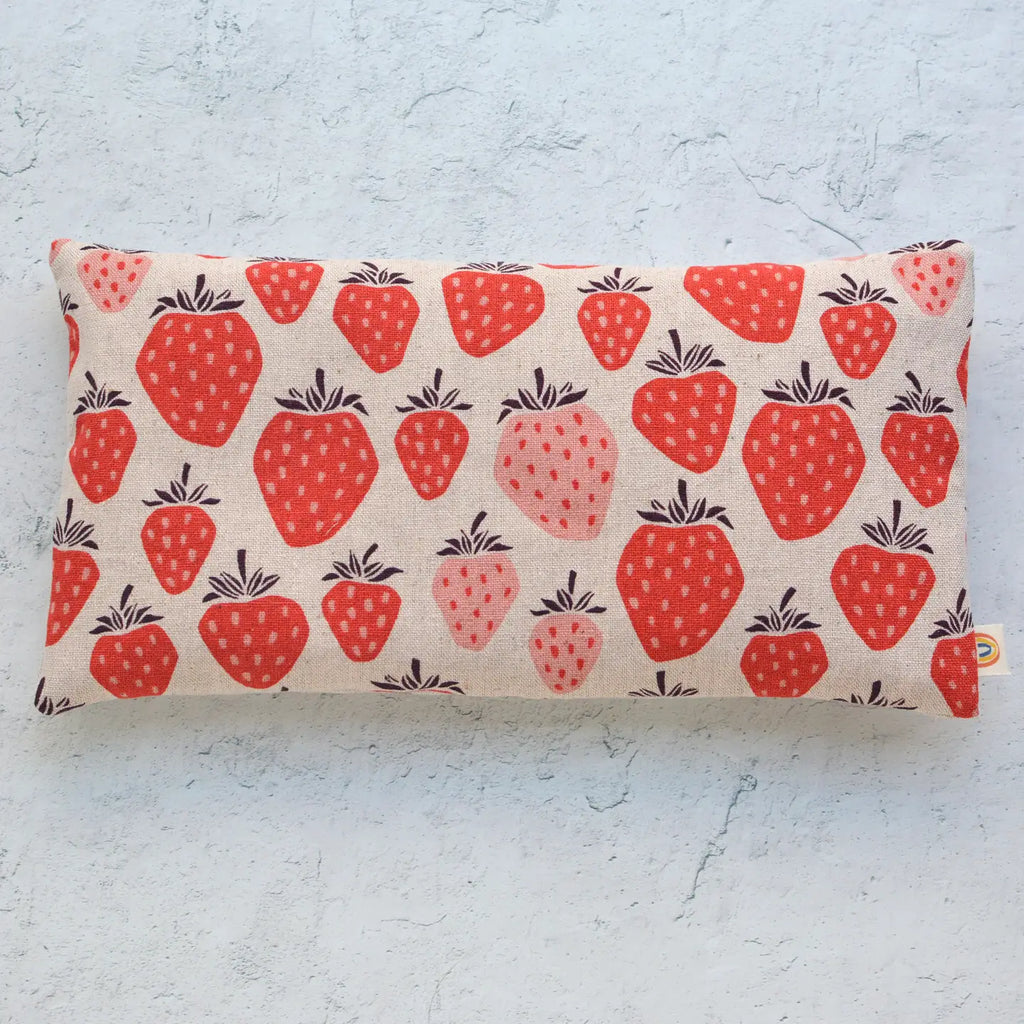 A rectangular cushion with a strawberry print design on a textured background.