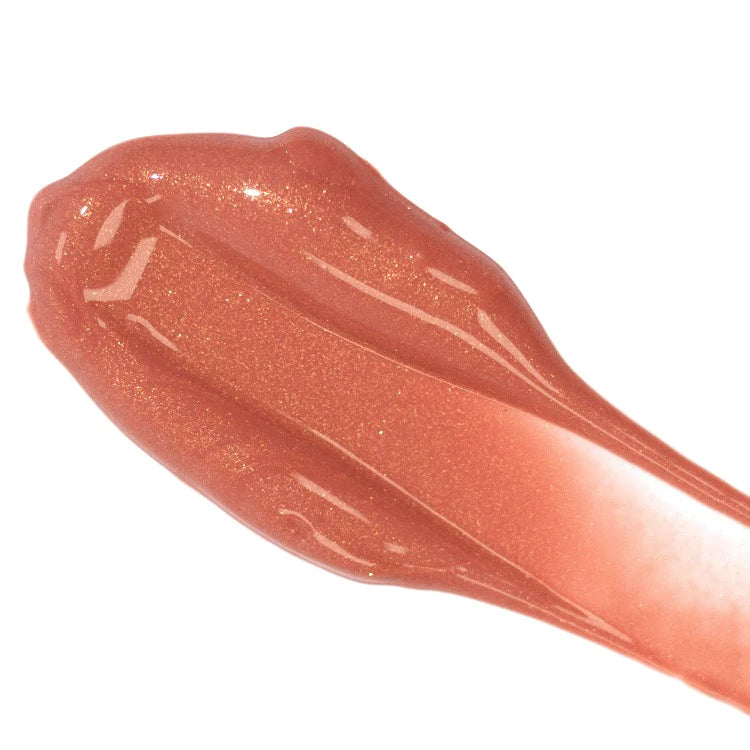 A swatch of shimmery peach lip gloss on a white background.