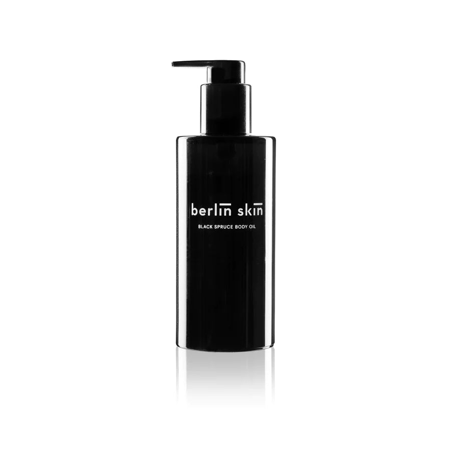 Black dispenser bottle of berlin skin black spruce body oil against a white background.