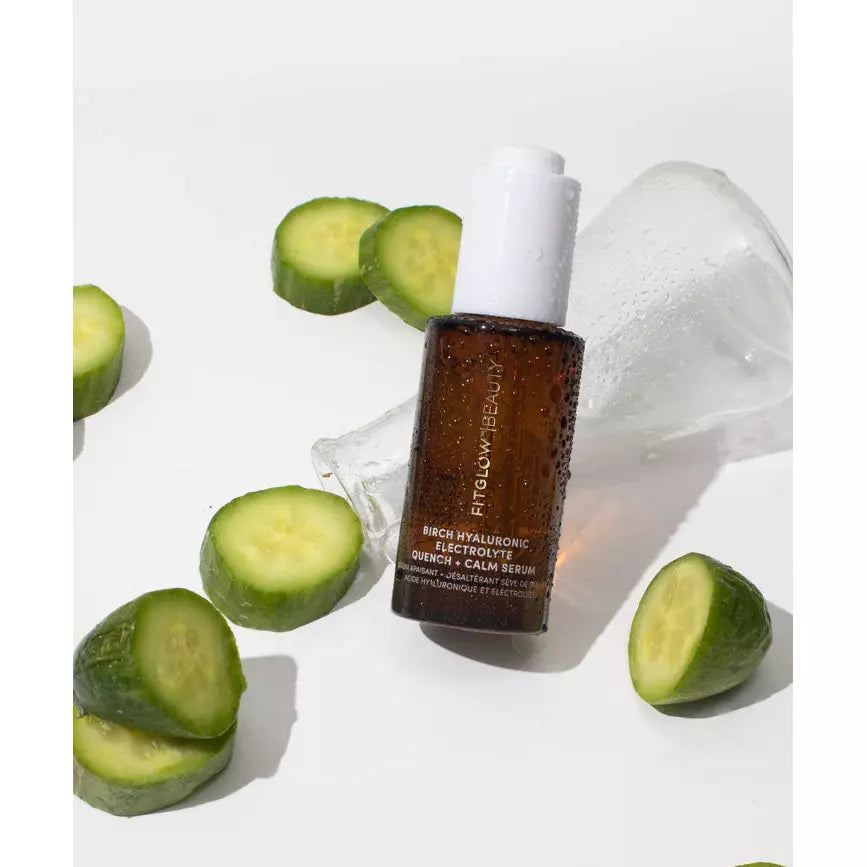 Skincare serum bottle with cucumber slices and ice on a white background.