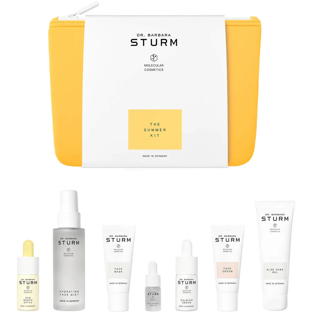 Dr. barbara sturm's skincare products arranged around a cosmetics bag with the label "the summer kit.