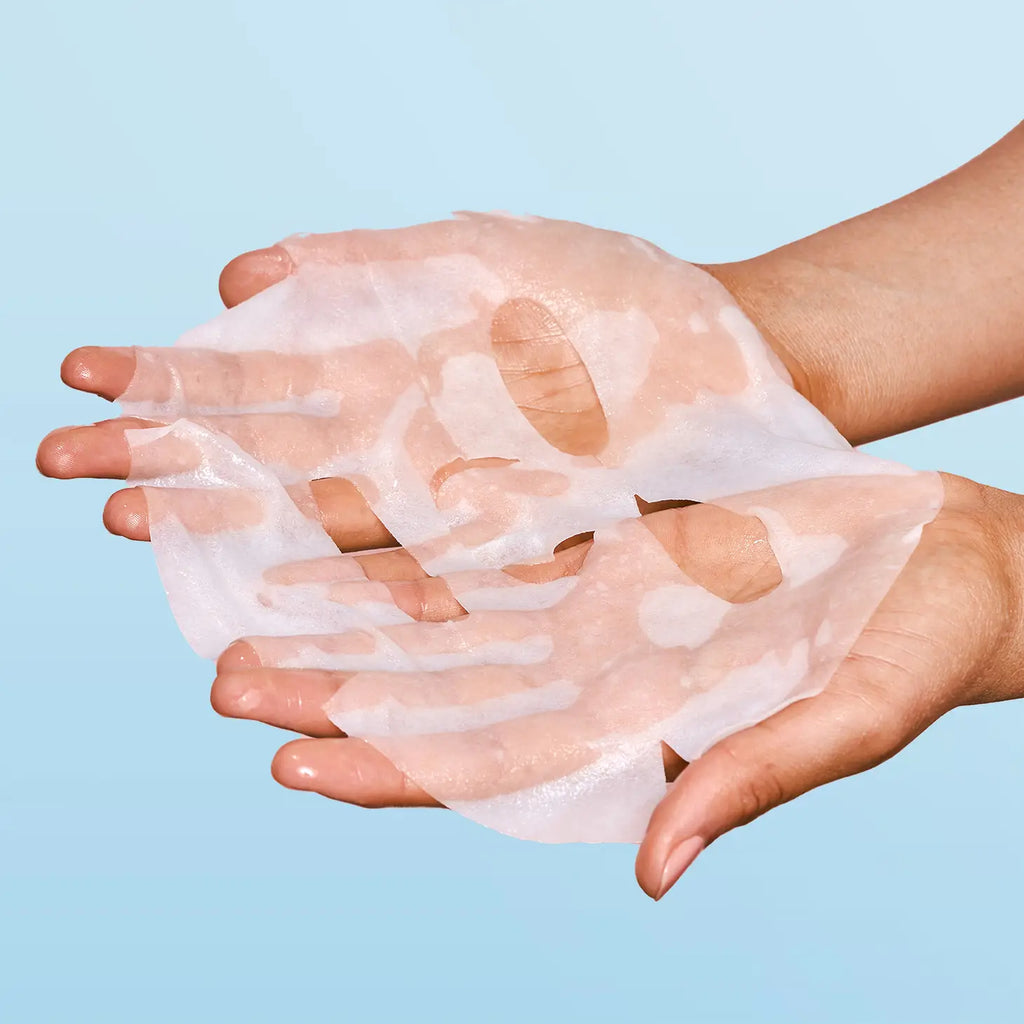 Two hands holding a translucent, peel-off face mask against a blue background.