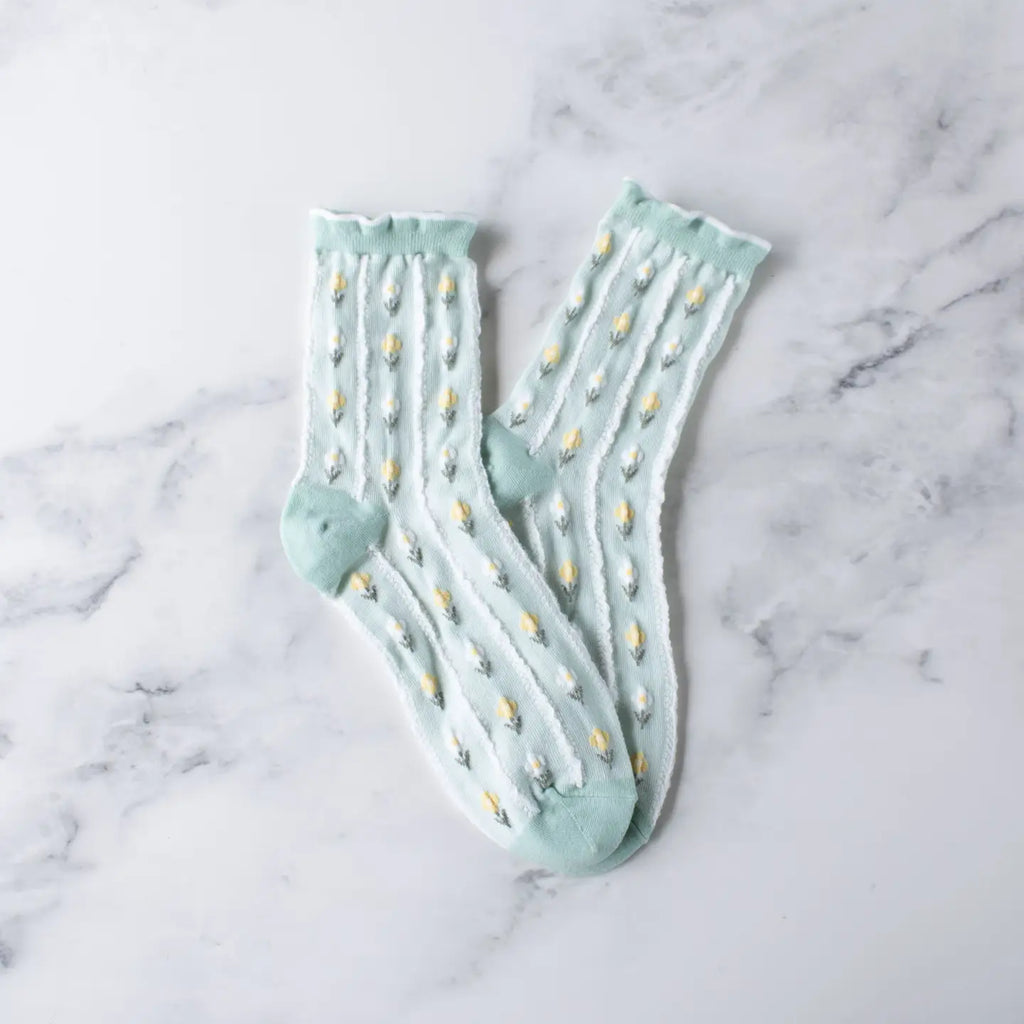 A pair of light blue socks with yellow flower pattern on a marble surface.