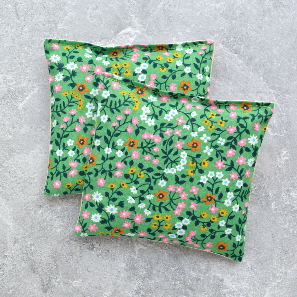 Two floral patterned fabric pillows on a gray background.