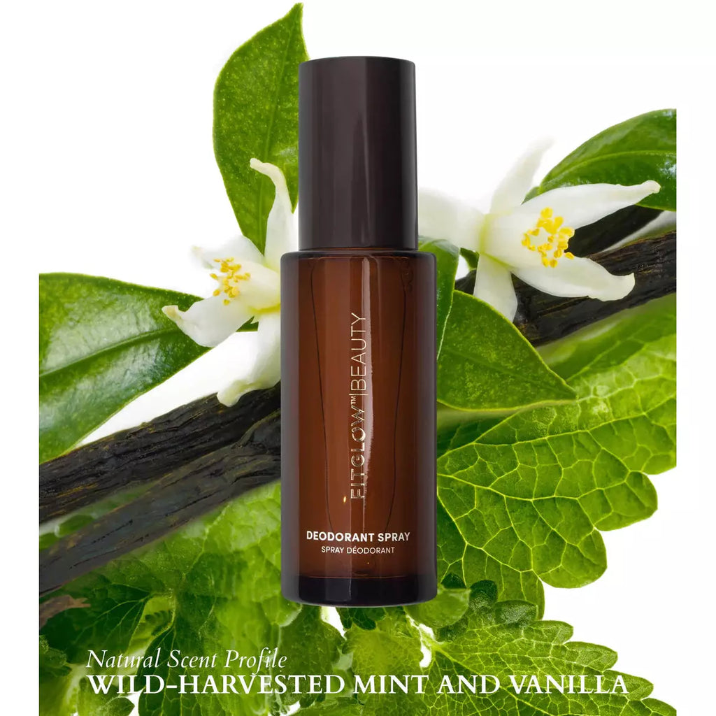A bottle of natural deodorant spray with a wild-harvested mint and vanilla scent, displayed against a background of fresh green leaves and white flowers.