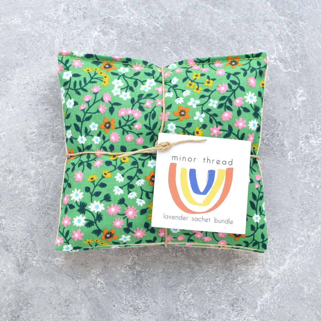 A floral fabric lavender sachet bundle with a brand label on a concrete surface.