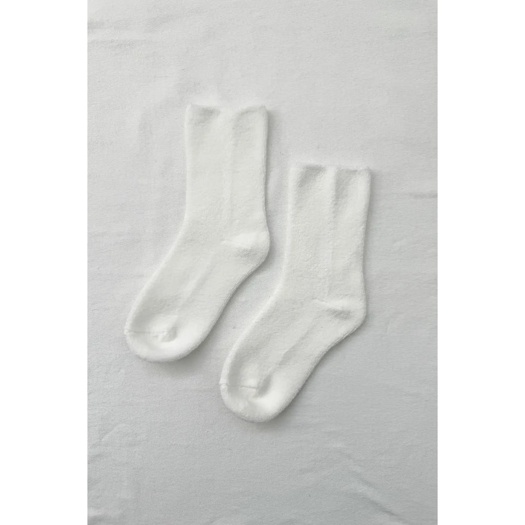 A pair of white socks laid flat on a textured surface.