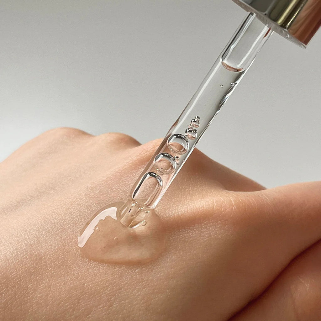 A dropper dispensing a clear liquid onto a person's hand.