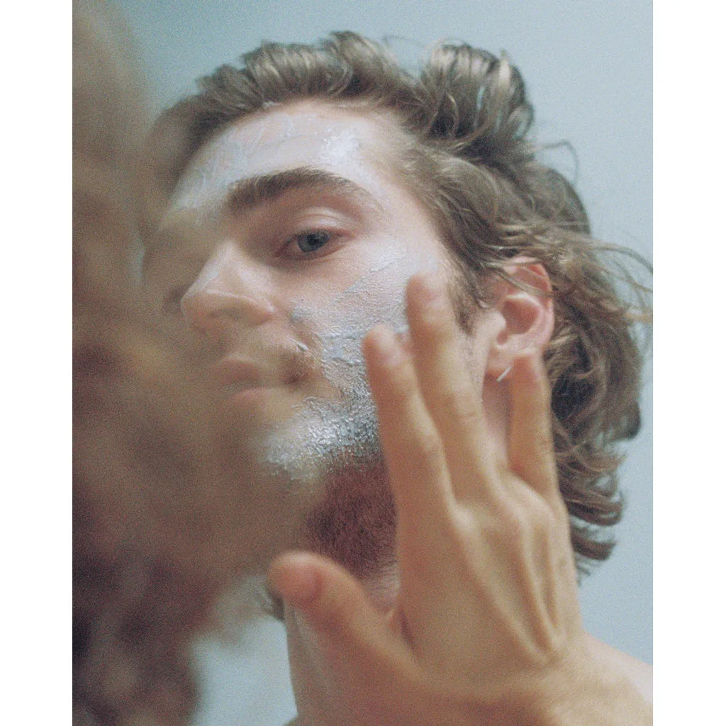A man applying lesse bioactive mask while looking into a mirror.