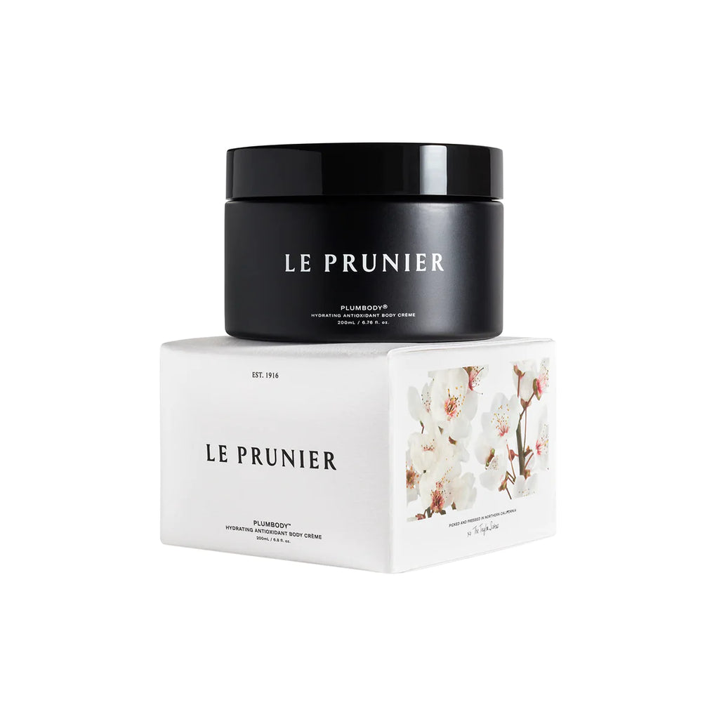 A jar of le prunier plum beauty oil atop its packaging box with floral design.