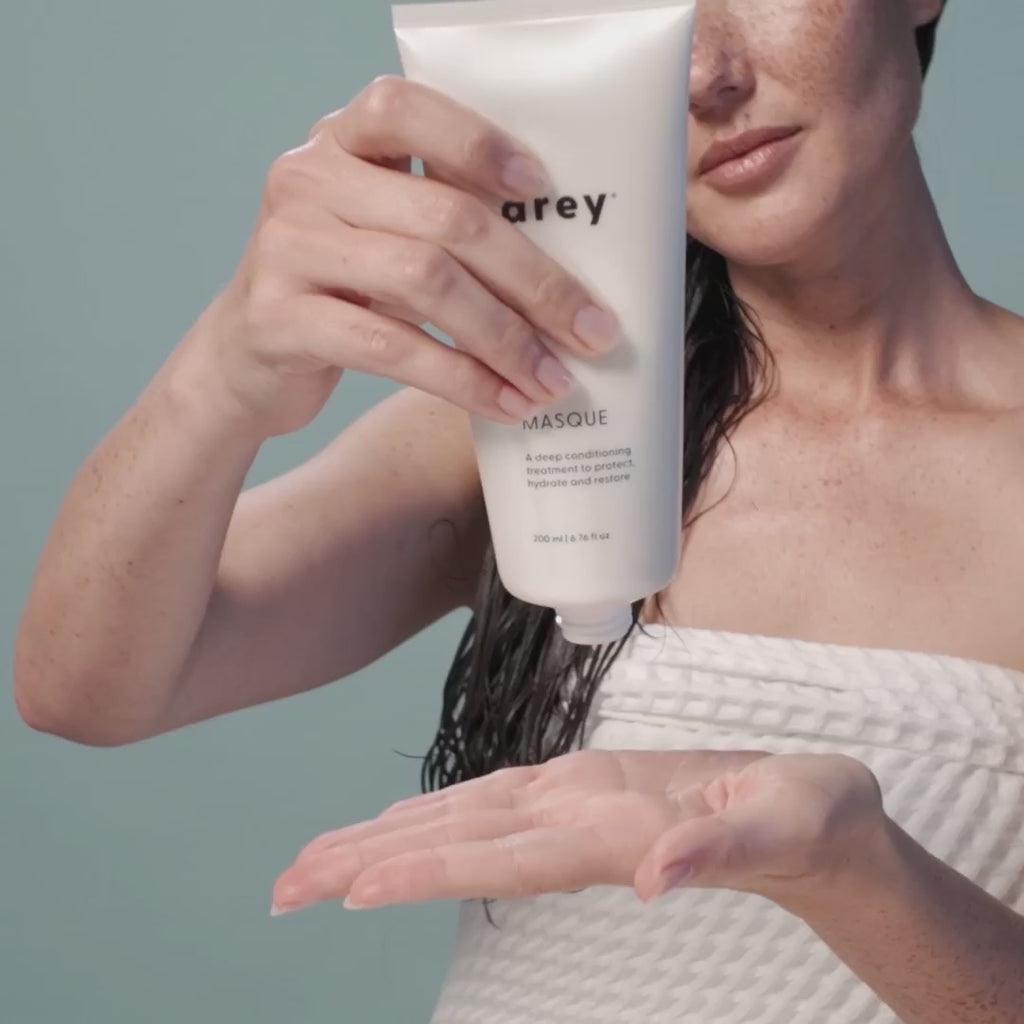 video of a person with long brown hair applying the Arey masque