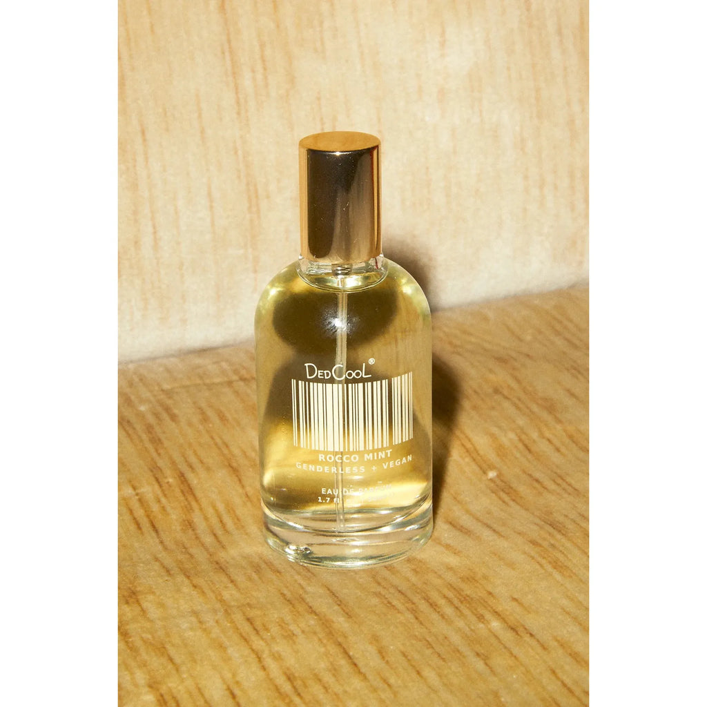Clear glass perfume bottle with gold cap on a wooden surface.