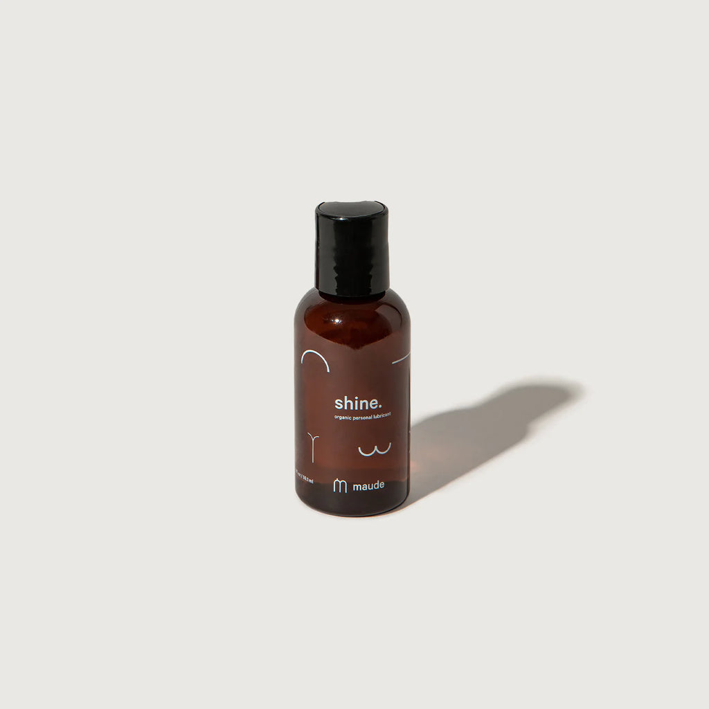 Brown bottle of "shine" product by maude against a plain white background.