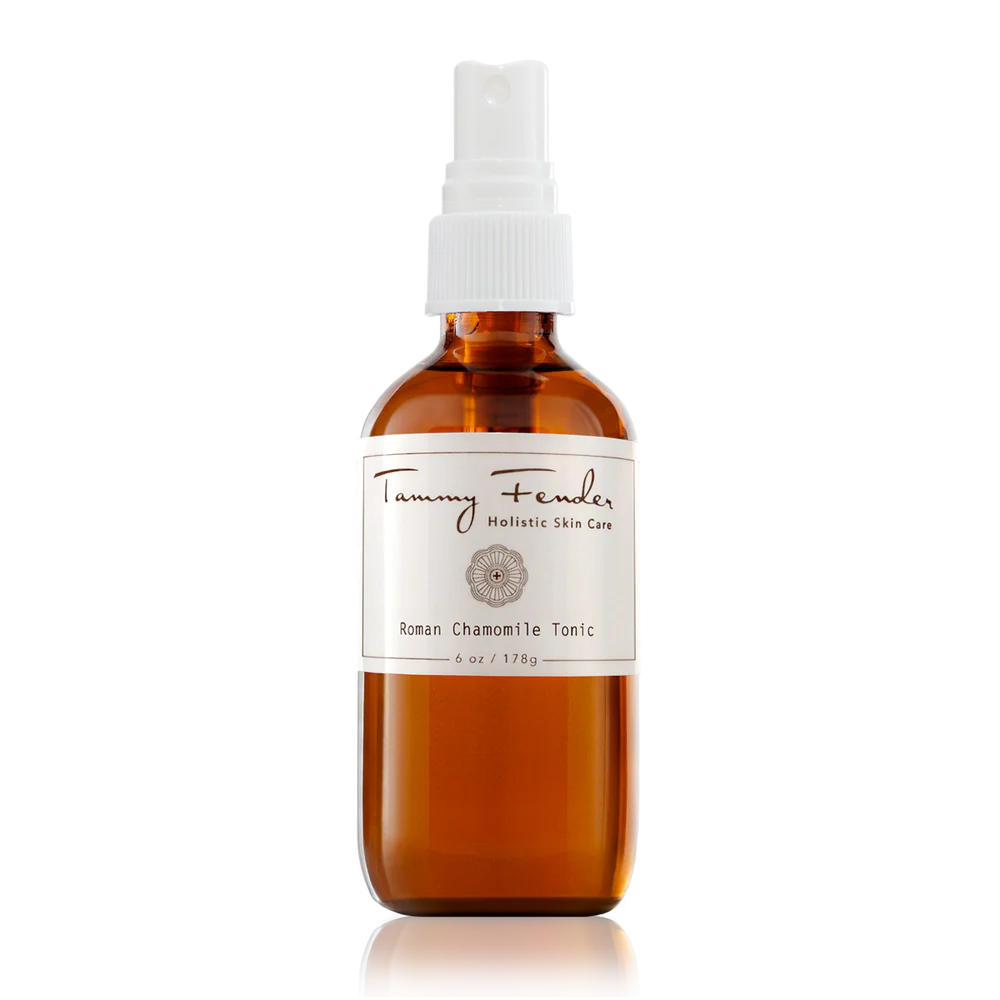 Amber glass bottle with spray nozzle labeled "tammy fender holistic skin care roman chamomile tonic" against a black background with white horizontal lines.
