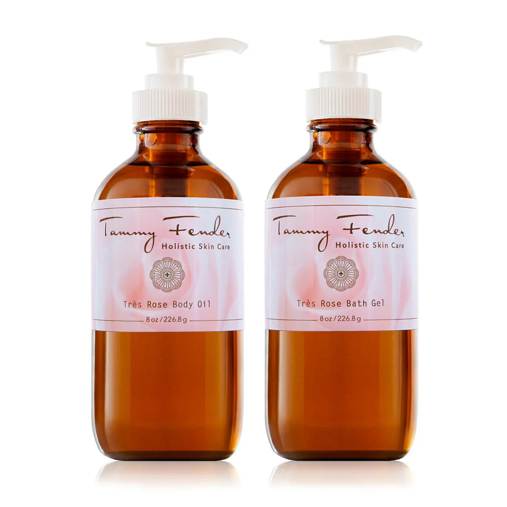 Two amber-colored pump bottles labeled under the "Très Rose Collection" from Tammy Fender Holistic Skin Care. One is the "Très Rose Body Oil," and the other is the "Très Rose Bath Gel." Each bottle contains 8oz/226.8g.