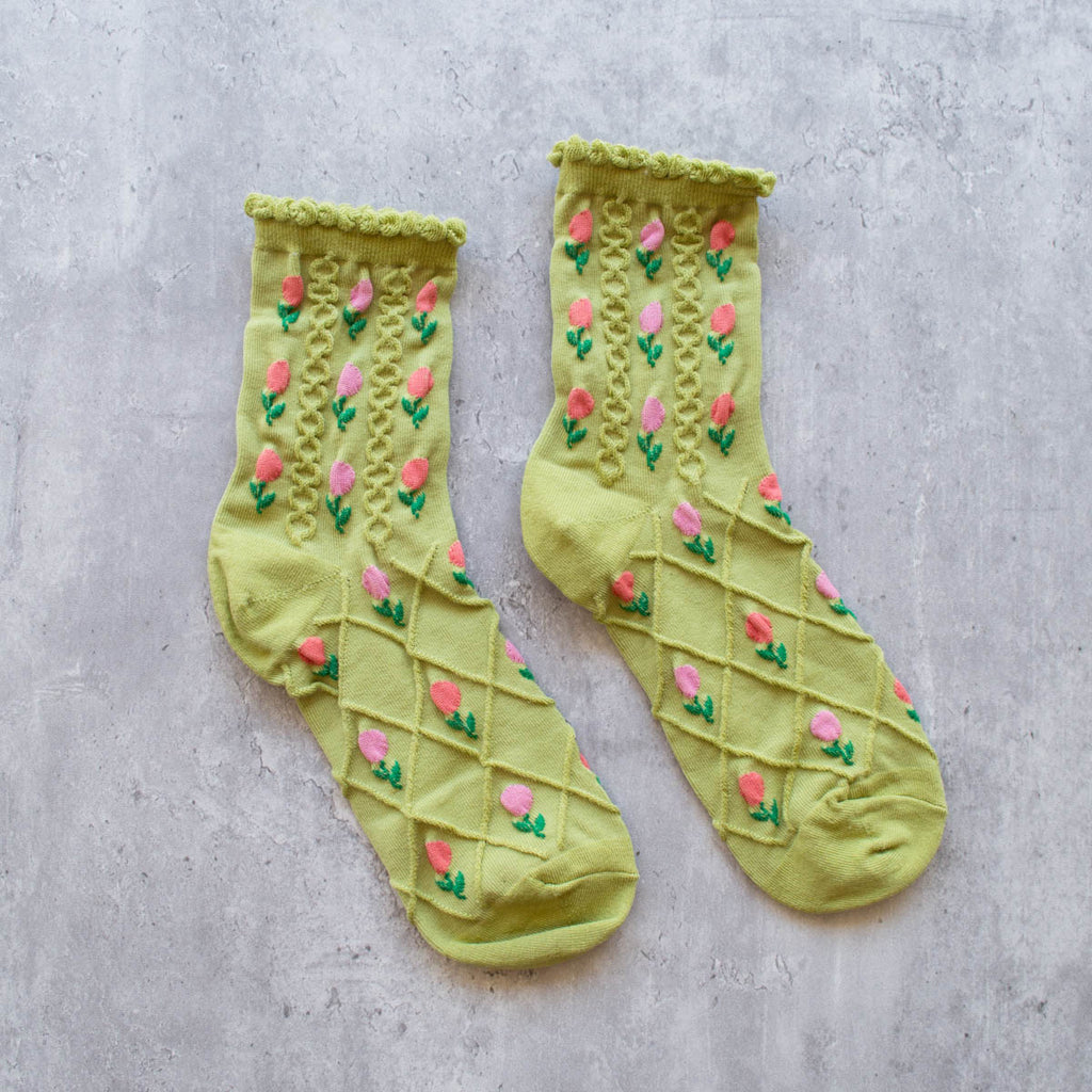 A pair of green socks with pink floral pattern on a gray background.
