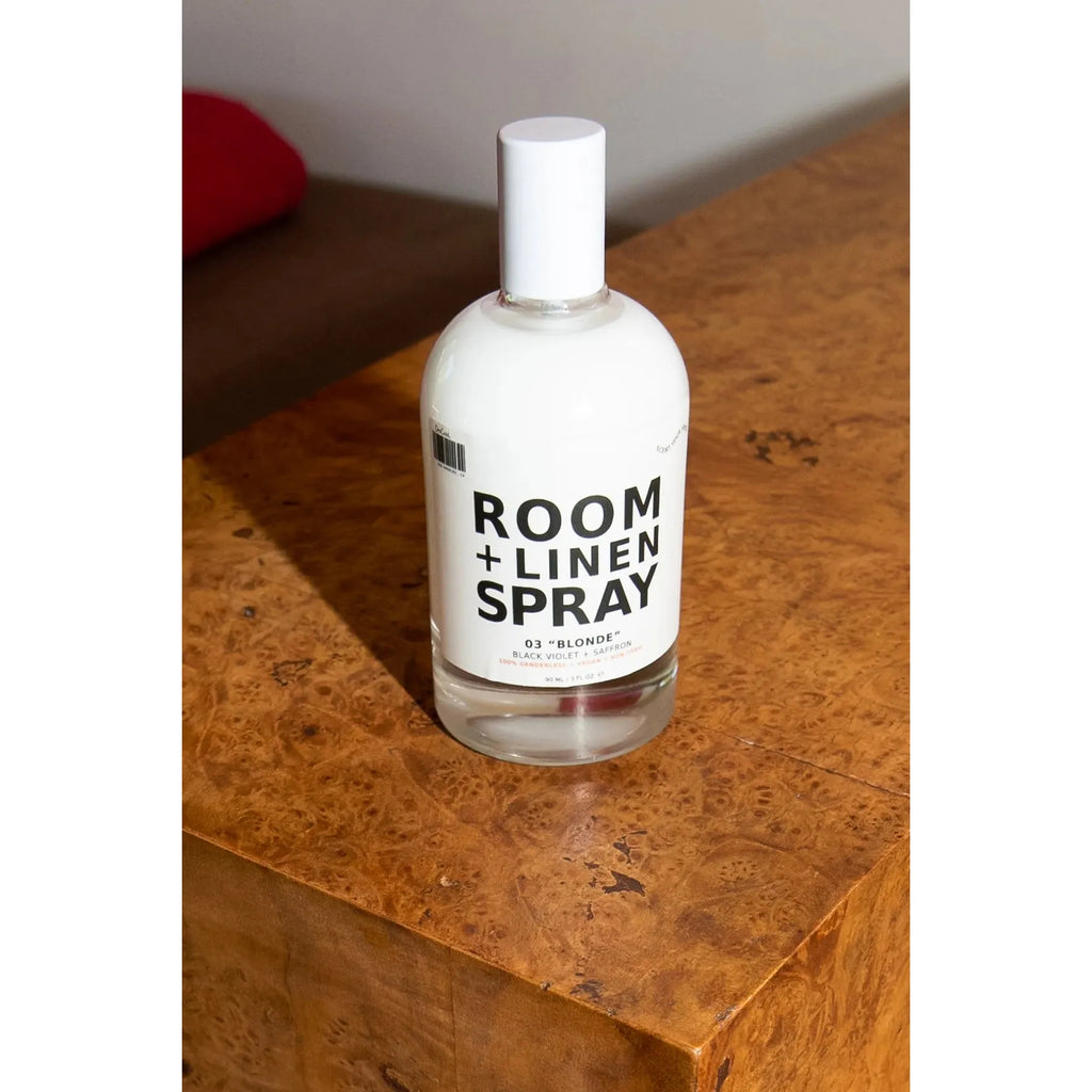 A bottle of room and linen spray placed on a wooden surface.
