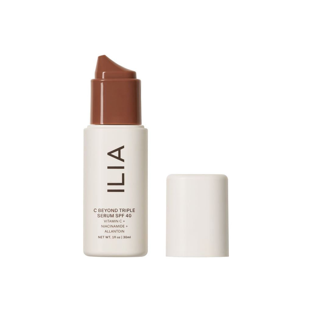 A bottle of ilia beauty serum with spf and its cap displayed next to it.