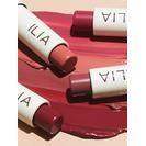 Three lipstick tubes labeled "ilia" beside swatches of their shades on a pink surface.