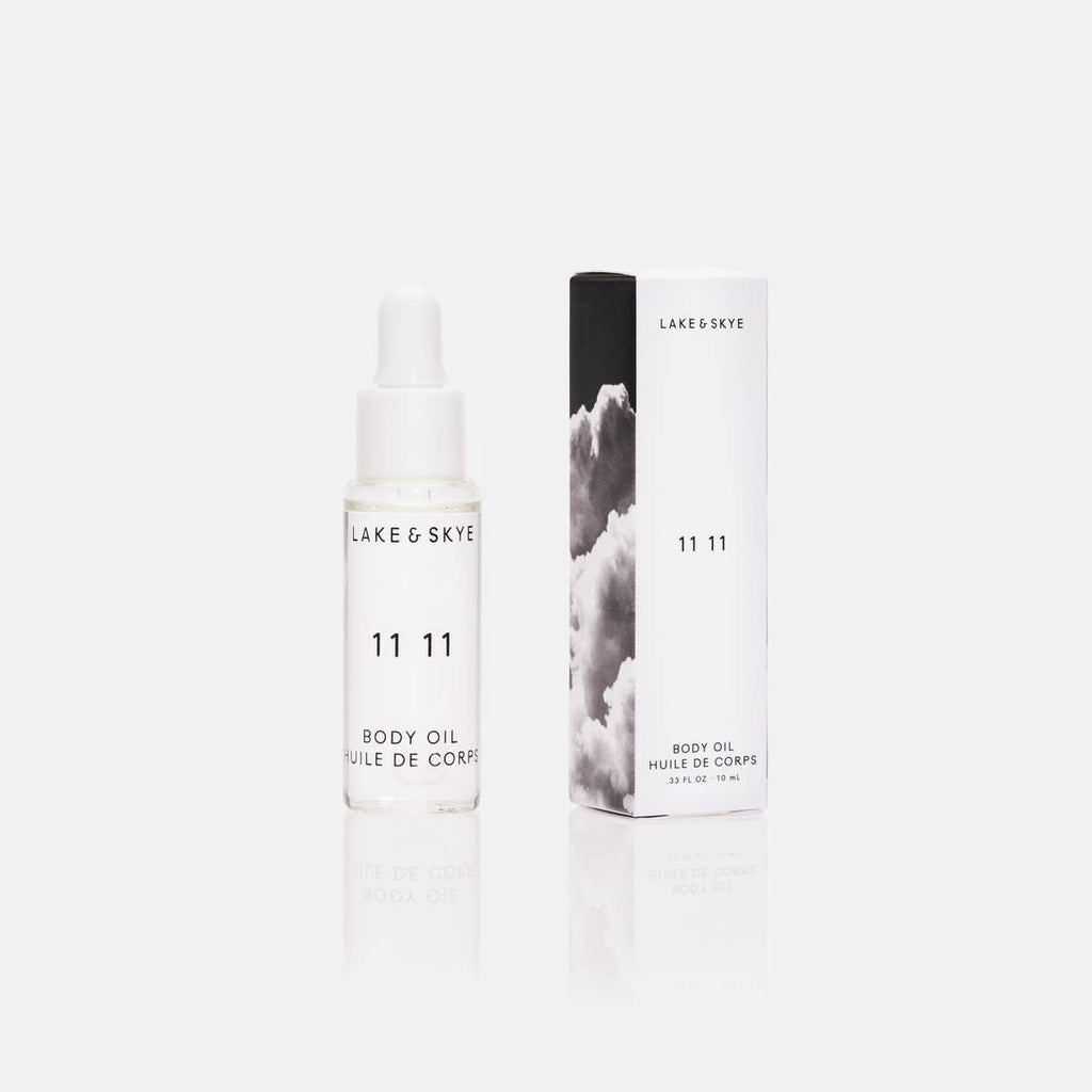 Bottle of lake & skye 11 11 body oil next to its packaging on a white background.