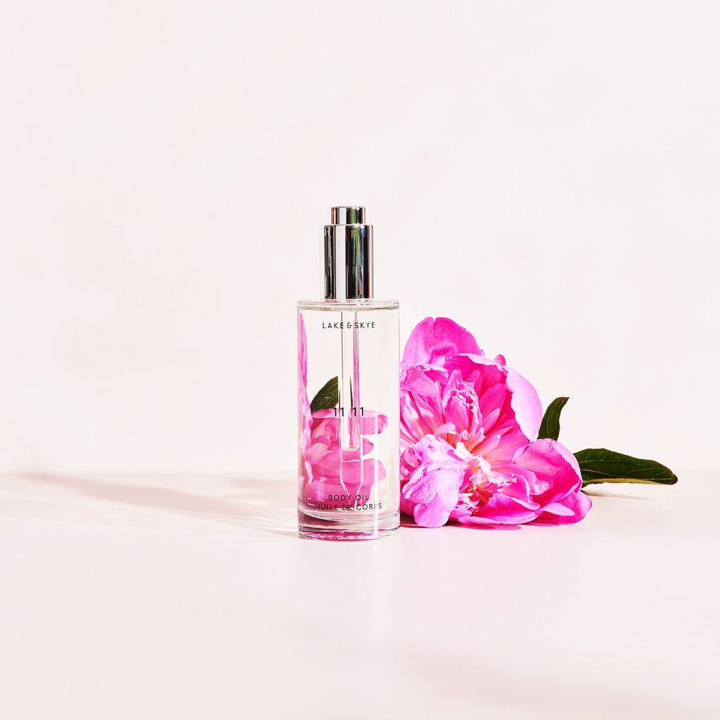 Elegant perfume bottle with a vibrant pink peony flower against a pastel background.