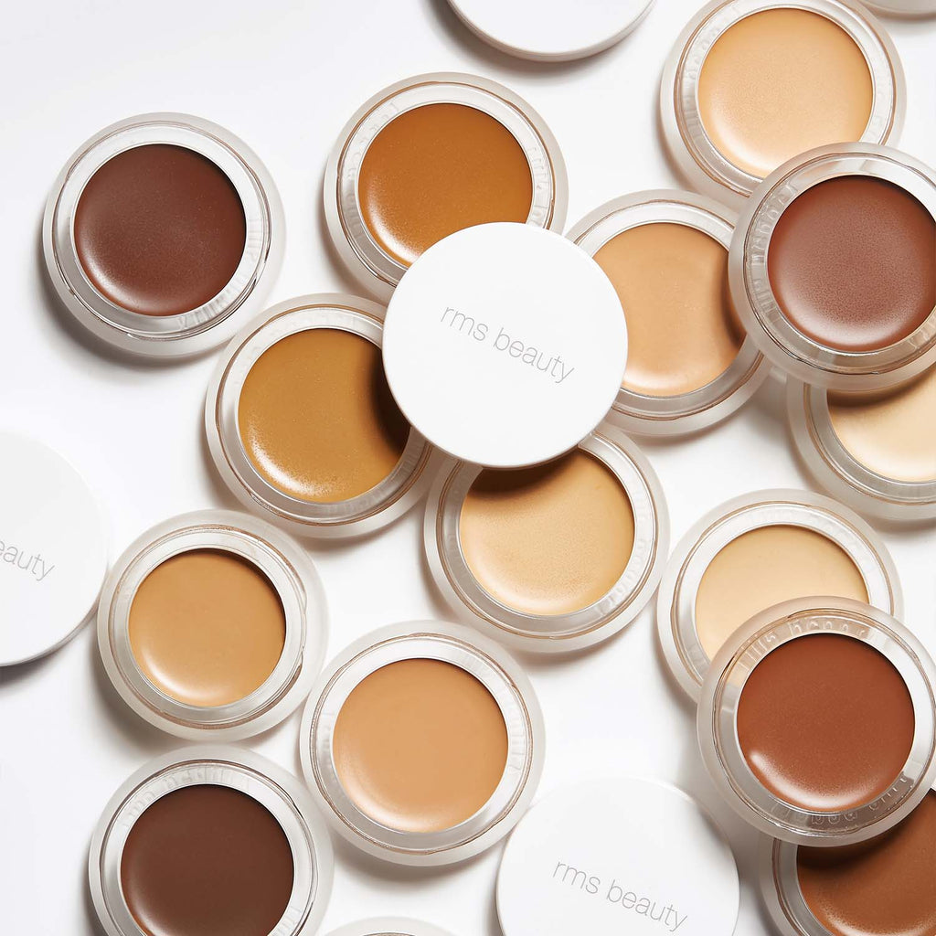 An assortment of rms beauty brand makeup foundation pots in various shades displayed on a plain background.