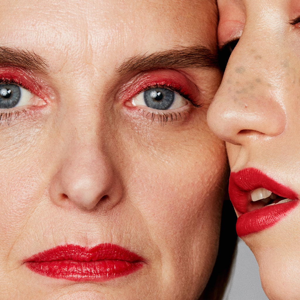 Two individuals with vibrant red makeup showcasing a close-up of their faces.