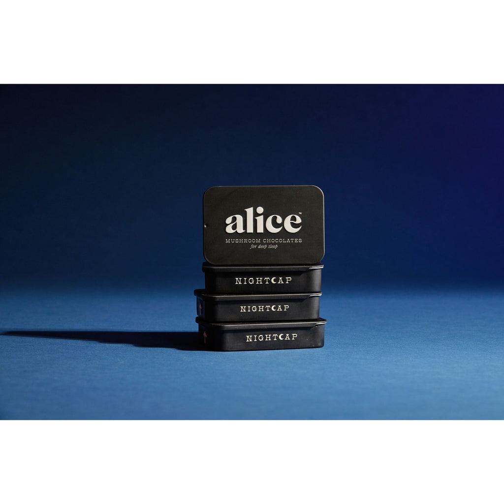Three stacked tins of 'alice nightcap mushroom chocolate' against a blue background.