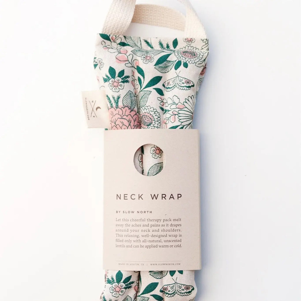 A floral-patterned neck wrap by slow north, designed for therapeutic use, displayed with its packaging.