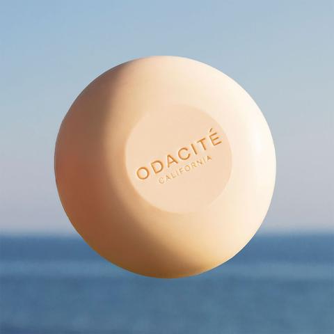 A bar of odacite soap against a blurred blue background.