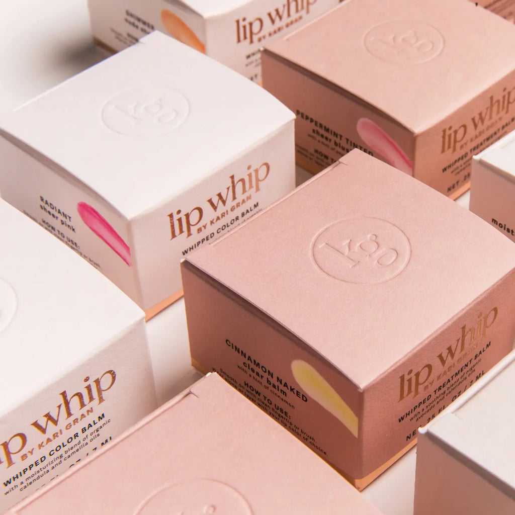 Boxes of lip whip products in pink packaging with logo displayed on top.