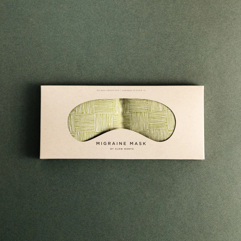 A packaged migraine mask lying on a green surface.