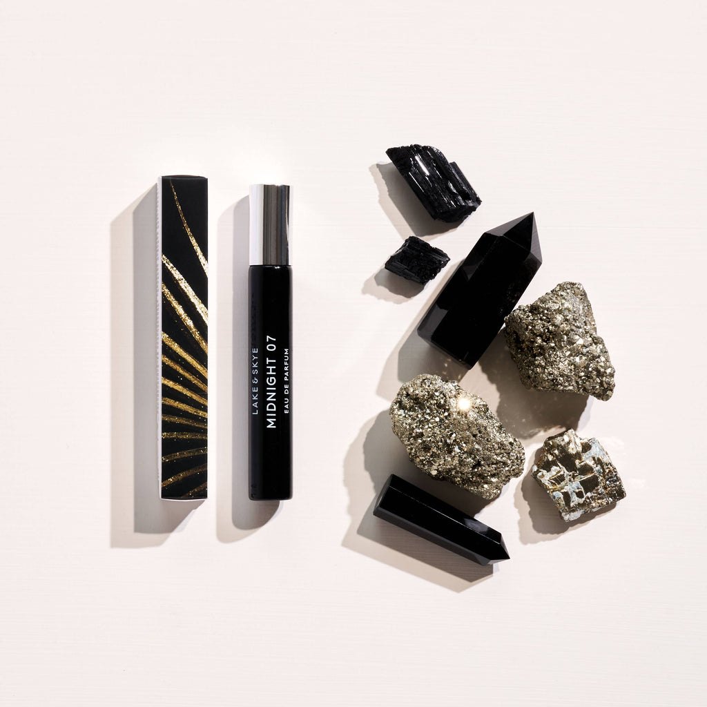 Cosmetic products alongside natural mineral stones on a plain background.