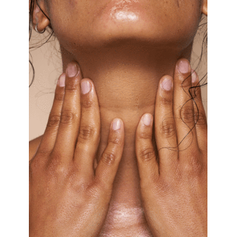 A person with hands gently placed on their throat area, displaying their neck and lower jaw.