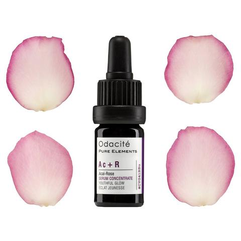 Bottle of odacite acai-rose serum concentrate surrounded by four rose petals.