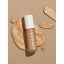 Liquid foundation and applicator with product smears on a neutral background.
